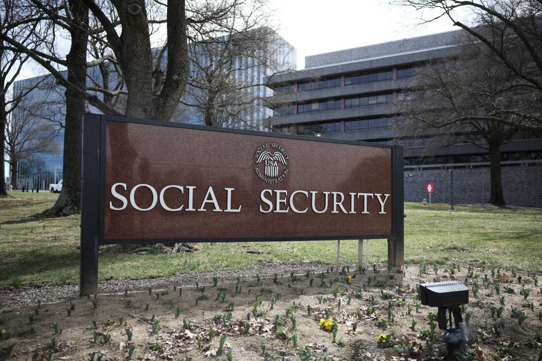 The Social Security Administration headquarters building in Woodlawn, Maryland on a clear day, with people walking near the entrance